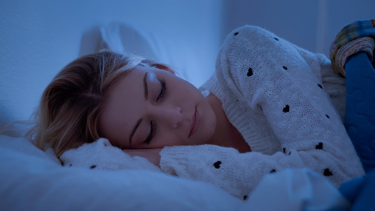 Schlafqualität: Frau liegt im Bett auf der Seite und schläft