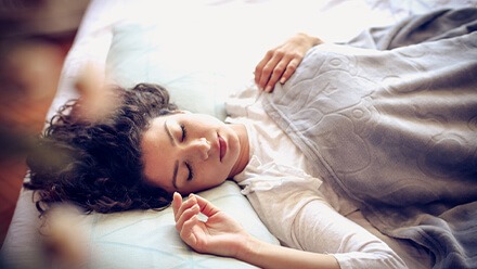 Schlafpositionen: Frau schläft in Rückenlage