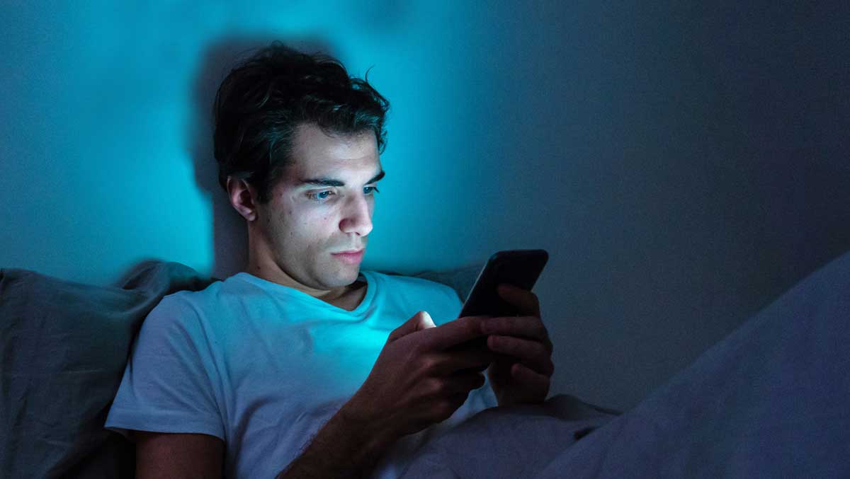 Blaues Licht: Mann mit Handy in Bett