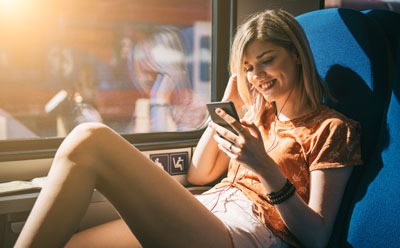 Frau schaut auf Smartphone beim Bahnfahren
