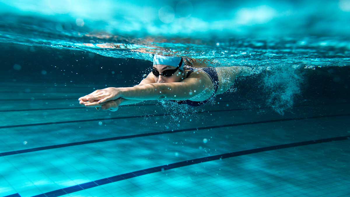 Tauchende Frau im Schwimmbad unter Wasser