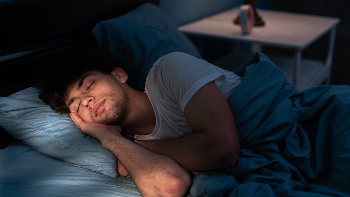 Mann schläft im halbdunklen Schlafzimmer